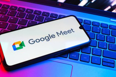 Prag, Çek Cumhuriyeti - 08 01 2025: Laptop klavyesinde bulunan bir cep telefonu Google Meet logosunu görüntüler. Google Meet video toplantıları ve çevrimiçi işbirliği için bir platformdur.