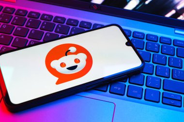 Prag, Çek Cumhuriyeti - 08 01 2025: Dizüstü bilgisayarın üzerinde duran bir cep telefonu Reddit logosunu gösterir. Reddit tartışma, haber ve toplum içeriği için bir platformdur.