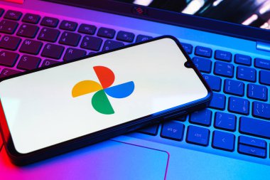 Prag, Çek Cumhuriyeti - 08 01 2025: Laptop klavyesinde duran bir cep telefonu Google Photos logosunu görüntüler. Google Fotoğrafları fotoğraf ve videoları saklamak ve düzenlemek için bir platformdur.