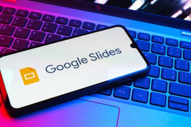 Prag, Çek Cumhuriyeti - 08 01 2025: Laptop klavyesinde duran bir cep telefonu Google Slides logosunu görüntüler. Google Slides sunumlar ve slayt gösterileri oluşturmak için bir platformdur.