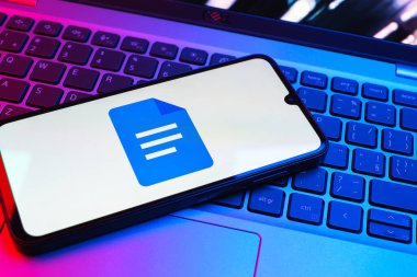 Prag, Çek Cumhuriyeti - 08 01 2025: Dizüstü bilgisayarda bulunan bir cep telefonu Google Docs logosunu görüntüler. Google Docs metin belgeleri oluşturmak ve düzenlemek için bir platformdur.