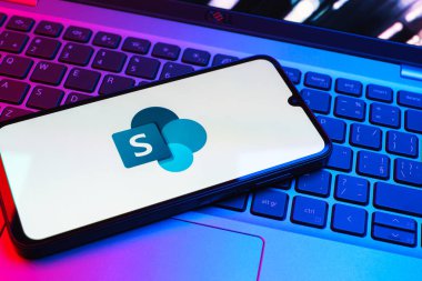Prag, Çek Cumhuriyeti - 08 01 2025: Dizüstü bilgisayarın üzerinde duran bir cep telefonu Microsoft Sharepoint logosunu gösteriyor. Microsoft Sharepoint işbirliği ve belge yönetimi için bir platformdur.