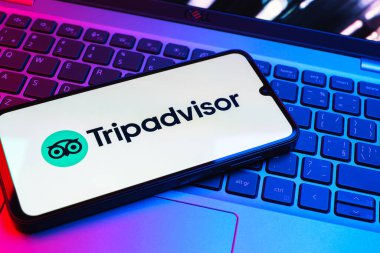 Prag, Çek Cumhuriyeti - 08 01 2025: Dizüstü bilgisayarın üzerinde bulunan bir cep telefonu TripDanışman logosunu gösteriyor. Seyahat danışmanı seyahat değerlendirmeleri, rezervasyonlar ve tavsiyeler için bir platformdur..