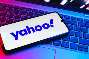 Prag, Çek Cumhuriyeti - 08 01 2025: Laptop klavyesinde duran bir cep telefonu Yahoo logosunu gösteriyor. Yahoo haber, e-posta ve internet hizmetleri için bir platformdur..