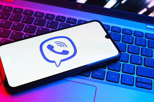Prag, Çek Cumhuriyeti - 08 01 2025: Dizüstü bilgisayarın üzerinde duran bir cep telefonu Viber logosunu gösteriyor. Viber aramalar, mesajlar ve medya paylaşımı için bir mesajlaşma uygulamasıdır.