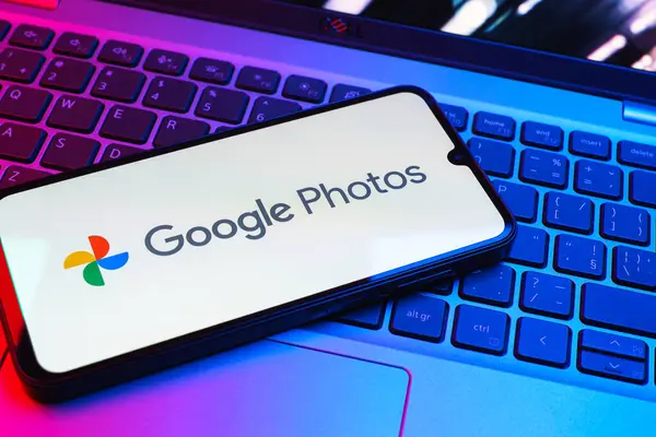 Prag, Çek Cumhuriyeti - 08 01 2025: Laptop klavyesinde duran bir cep telefonu Google Photos logosunu görüntüler. Google Fotoğrafları fotoğraf ve videoları saklamak ve düzenlemek için bir platformdur.