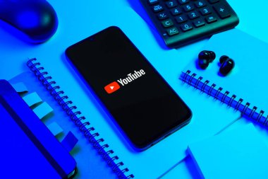 Prag, Çek Cumhuriyeti - 08 18 2025: Merkezde Youtube logosu sergilenen bir cep telefonu ile ofis malzemeleri düzenlemesi. Youtube dünya çapında videoları izlemek ve paylaşmak için bir platform.