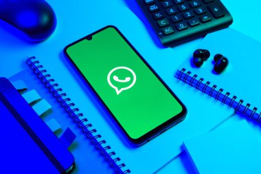 Prag, Çek Cumhuriyeti - 08 18 2025: Ofis malzemelerinin merkezde WhatsApp logosunu gösteren bir cep telefonu ile düzenlenmesi. WhatsApp mesaj, çağrı ve medya göndermek için bir uygulamadır.