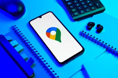 Prag, Çek Cumhuriyeti - 08 18 2025: Merkezde Google Maps logosunu gösteren bir cep telefonu ile ofis malzemeleri düzenlemesi. Google Maps haritalar, navigasyon ve konum hizmetleri için bir platformdur.
