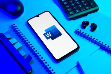 Prag, Çek Cumhuriyeti - 08 18 2025: Merkezinde Word logosu sergilenen bir cep telefonu ile ofis malzemeleri düzenlemesi. Word belge yaratmak ve düzenlemek için bir yazılımdır..