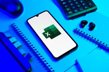Prag, Çek Cumhuriyeti - 08 18 2025: Excel logosu sergilenen bir cep telefonu ile ofis malzemeleri düzenlemesi. Excel, tablo, veri analizi ve hesaplamalar için bir yazılımdır..