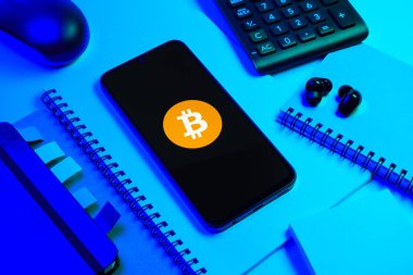 Prag, Çek Cumhuriyeti - 08 18 2025: Merkezde Bitcoin logosu sergilenen bir cep telefonu ile ofis malzemeleri düzenlemesi. Bitcoin merkezi olmayan işlemler için dijital bir kripto para birimidir.