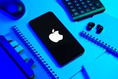 Prag, Çek Cumhuriyeti - 08 18 2025: Merkezi Apple logosunu gösteren bir cep telefonu ile ofis malzemeleri düzenlemesi. Apple iPhone, bilgisayar ve hizmet üreten bir teknoloji şirketidir..