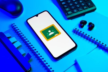 Prag, Çek Cumhuriyeti - 08 18 2025: Merkezde Google Sınıfı logosunu gösteren bir cep telefonu ile ofis malzemeleri düzenlemesi. Google Sınıfı, sınıfları ve eğitim içeriğini yönetmek için bir platformdur.