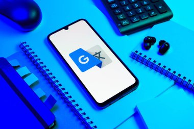 Prag, Çek Cumhuriyeti - 08 18 2025: Merkezde Google Translate logosunu gösteren bir cep telefonu ile ofis malzemeleri düzenlemesi. Google Çevirisi metni ve konuşmayı diller arası çevirmek için bir platformdur..