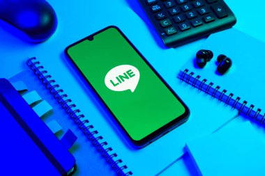 Prag, Çek Cumhuriyeti - 08 18 2025: Merkezinde hat logosu sergilenen bir cep telefonu ile ofis malzemeleri düzenlemesi. Line aramalar, mesajlar ve çokluortam paylaşımı için bir mesajlaşma uygulamasıdır.