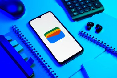 Prag, Çek Cumhuriyeti - 08 18 2025: Merkezde Google Cüzdan logosunu gösteren bir cep telefonu ile ofis malzemeleri düzenlemesi. Google Cüzdanı dijital ödeme yöntemlerini depolamak ve kullanmak için bir platformdur.