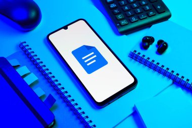 Prag, Çek Cumhuriyeti - 08 18 2025: Merkezde Google Docs logosunu gösteren bir cep telefonu ile ofis malzemeleri düzenlemesi. Google Docs metin belgeleri oluşturmak ve düzenlemek için bir platformdur.