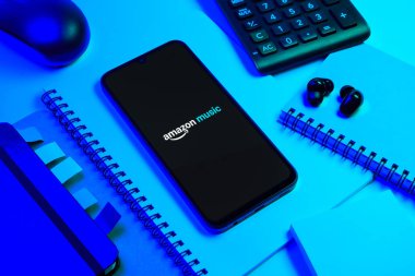 Prag, Çek Cumhuriyeti - 08 18 2025: Merkezde Amazon Müzik logosu sergilenen bir cep telefonu ile ofis malzemeleri düzenlemesi. Amazon Müzik müzik müzik için bir platformdur..