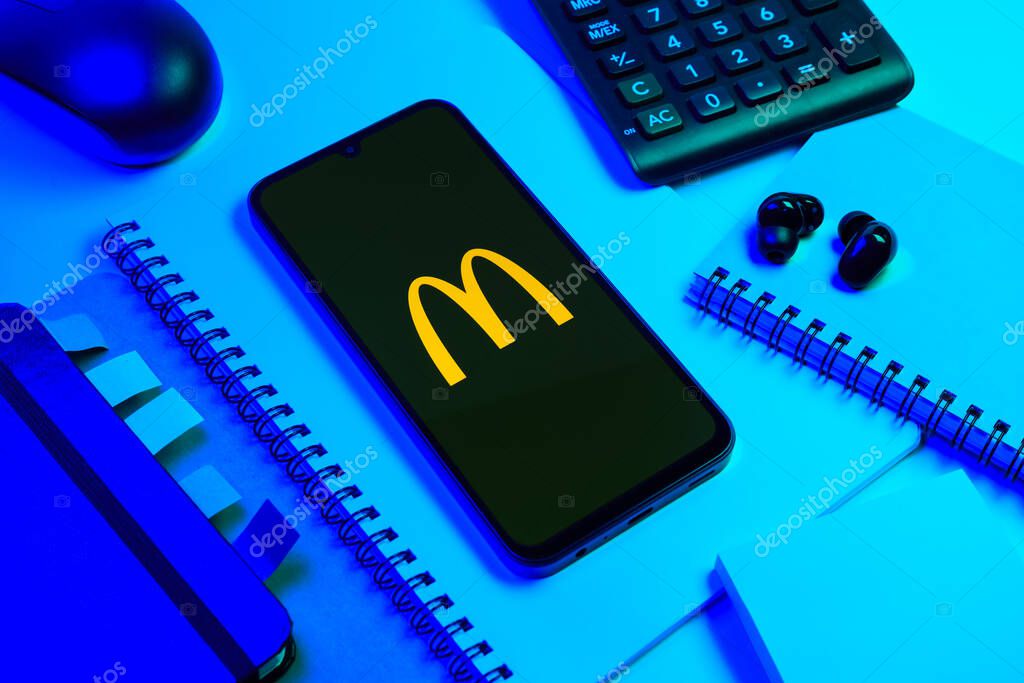 Prague, Czechia - 08 18 2025: An arrangement of office supplies with a mobile phone in the center displaying McDonalds logo. McDonalds is a fast-food chain serving burgers, fries, and more.