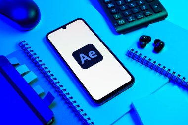Prag, Çek Cumhuriyeti - 08 18 2025: Ofis malzemelerinin merkezde After Effects logosu sergilenen bir cep telefonu ile düzenlenmesi. After Effects hareket grafikleri ve görsel efektler için bir yazılımdır..