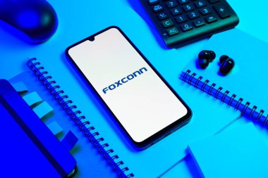 Prag, Çek Cumhuriyeti - 08 18 2025: Merkezde Foxconn logosunu gösteren bir cep telefonu ile ofis malzemeleri düzenlemesi. Foxconn elektronik ve parça üreten bir şirket..