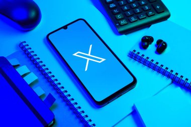 Prag, Çek Cumhuriyeti - 08 18 2025: Merkezinde X logosu sergilenen bir cep telefonu ile ofis malzemeleri düzenlemesi. X, kısa gönderileri ve güncellemeleri paylaşmak için bir platformdur.