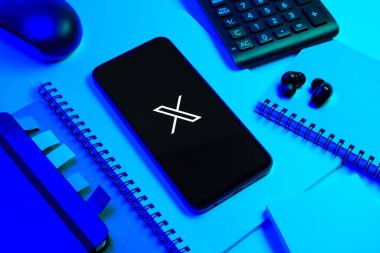 Prag, Çek Cumhuriyeti - 08 18 2025: Merkezinde X logosu sergilenen bir cep telefonu ile ofis malzemeleri düzenlemesi. X, kısa gönderileri ve güncellemeleri paylaşmak için bir platformdur.