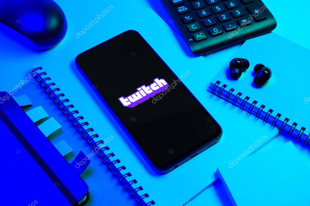 Prague, Czechia - 08 18 2025: An arrangement of office supplies with a mobile phone in the center displaying Twitch logo. Twitch is a platform for live streaming games and content.