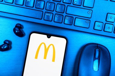 Prague, Czechia - 08 09 2025: A top-down view of a desk with a phone displaying the McDonalds logo. McDonalds is a fast-food chain serving burgers, fries, and more.