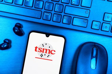 Prague, Czechia - 08 09 2025: A top-down view of a desk with a phone displaying the TSMC logo. TSMC is a semiconductor foundry manufacturing chips for tech companies.
