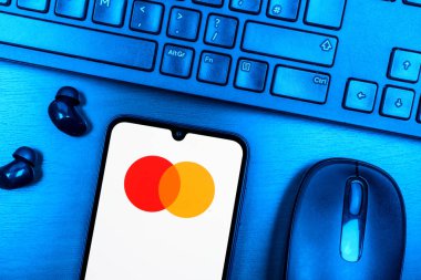 Prague, Czechia - 08 09 2025: A top-down view of a desk with a phone displaying the Mastercard logo. Mastercard is a financial company providing payment cards and services.