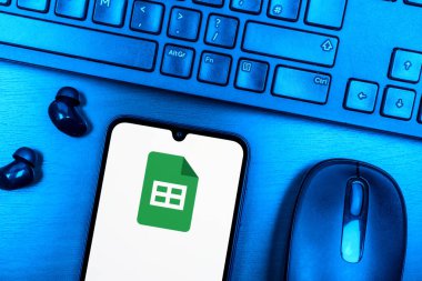 Prague, Czechia - 08 09 2025: A top-down view of a desk with a phone displaying the Google Sheets logo. Google Sheets is a platform for creating and managing spreadsheets.