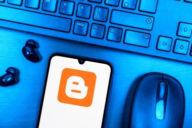 Prague, Czechia - 08 09 2025: A top-down view of a desk with a phone displaying the Blogger logo. Blogger is a platform for creating and publishing blogs.