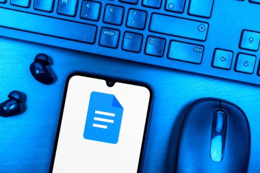 Prague, Czechia - 08 09 2025: A top-down view of a desk with a phone displaying the Google Docs logo. Google Docs is a platform for creating and editing text documents.