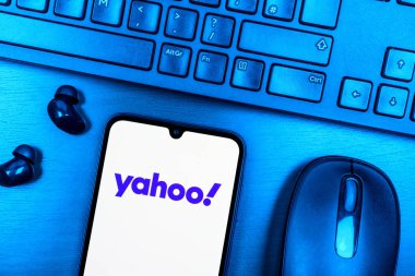 Prague, Czechia - 08 09 2025: A top-down view of a desk with a phone displaying the Yahoo logo. Yahoo is a platform for news, email, and online services.