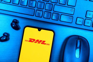 Prague, Czechia - 08 09 2025: A top-down view of a desk with a phone displaying the DHL logo. DHL is a logistics company offering international shipping services.
