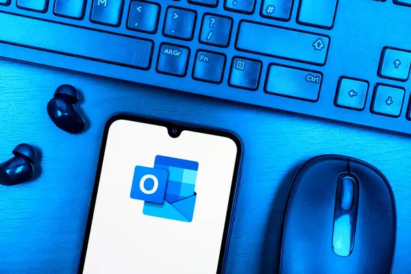 Prag, Çek Cumhuriyeti - 08 09 2025: Outlook logosunu gösteren bir telefonun olduğu bir masanın yukarıdan görünüşü. Outlook iletileri göndermek ve yönetmek için bir e- posta platformudur.