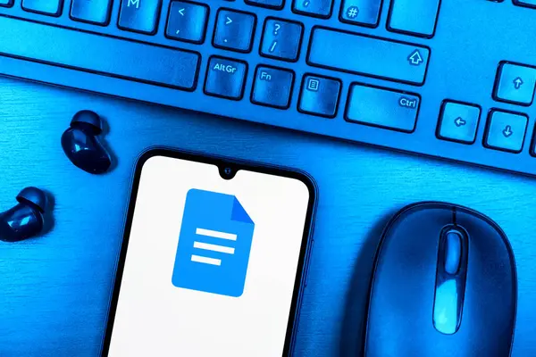 Prague, Czechia - 08 09 2025: A top-down view of a desk with a phone displaying the Google Docs logo. Google Docs is a platform for creating and editing text documents.