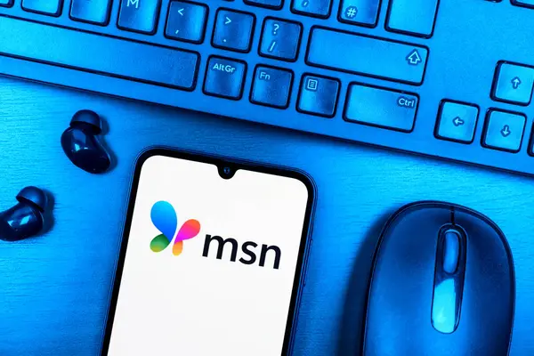 Prague, Czechia - 08 09 2025: A top-down view of a desk with a phone displaying the MSN logo. MSN is a platform for news, email, and online services.