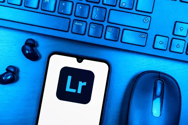 Prague, Czechia - 08 09 2025: A top-down view of a desk with a phone displaying the Lightroom logo. Lightroom is a software for photo editing and management.