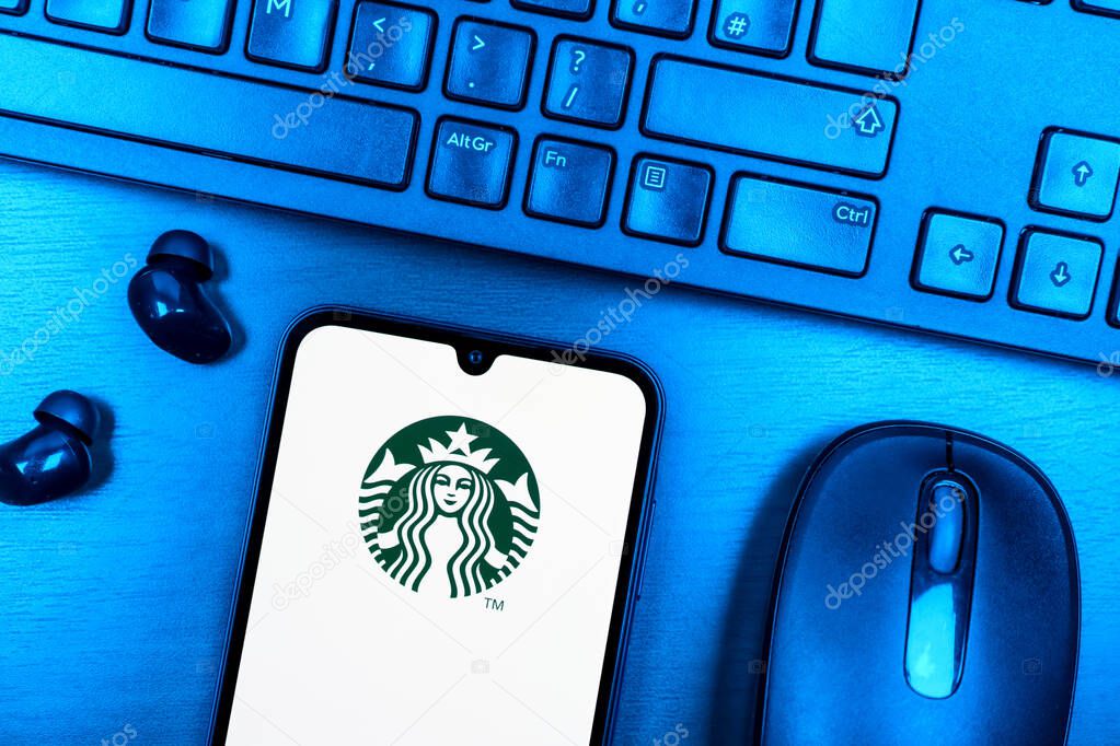 Prague, Czechia - 08 09 2025: A top-down view of a desk with a phone displaying the Starbucks logo. Starbucks is a global coffeehouse chain serving beverages and food.