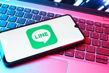 Prag, Çek Cumhuriyeti - 08 01 2025: Dizüstü bilgisayarın üzerinde duran bir cep telefonu Hat logosunu gösterir. Line aramalar, mesajlar ve çokluortam paylaşımı için bir mesajlaşma uygulamasıdır.