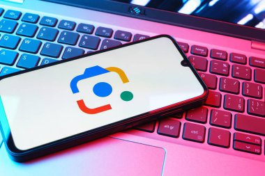 Prag, Çek Cumhuriyeti - 08 01 2025: Bir klavyenin üzerinde duran bir cep telefonu Google Lens logosunu görüntüler. Google Lens, resimlerdeki görsel arama ve bilgi için kullanılan bir araçtır..