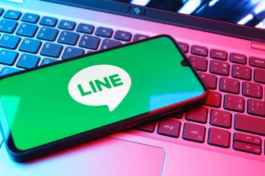 Prag, Çek Cumhuriyeti - 08 01 2025: Dizüstü bilgisayarın üzerinde duran bir cep telefonu Hat logosunu gösterir. Line aramalar, mesajlar ve çokluortam paylaşımı için bir mesajlaşma uygulamasıdır.