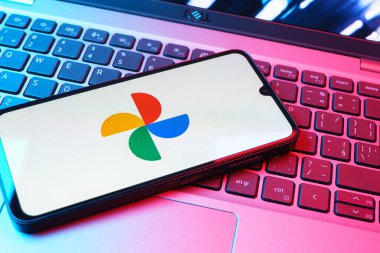 Prag, Çek Cumhuriyeti - 08 01 2025: Laptop klavyesinde duran bir cep telefonu Google Photos logosunu görüntüler. Google Fotoğrafları fotoğraf ve videoları saklamak ve düzenlemek için bir platformdur.