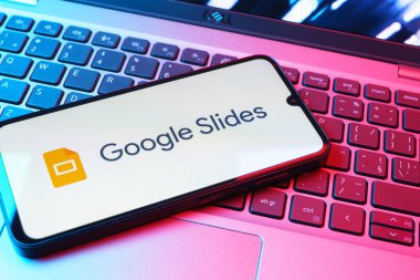 Prag, Çek Cumhuriyeti - 08 01 2025: Laptop klavyesinde duran bir cep telefonu Google Slides logosunu görüntüler. Google Slides sunumlar ve slayt gösterileri oluşturmak için bir platformdur.