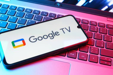 Prag, Çek Cumhuriyeti - 08 01 2025: Laptop klavyesinde uzanan bir cep telefonu Google TV logosunu gösteriyor. Google TV film, program ve uygulamalar için bir platformdur..