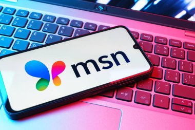 Prag, Çek Cumhuriyeti - 08 01 2025: Dizüstü bilgisayarın üzerinde duran bir cep telefonu MSN logosunu gösterir. MSN haber, e-posta ve çevrimiçi hizmetler için bir platformdur.