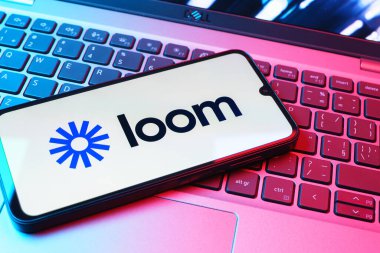 Prag, Çek Cumhuriyeti - 08 01 2025: Laptop klavyesinde duran bir cep telefonu Loom logosunu gösterir. Loom video mesajlarını kaydetmek ve paylaşmak için bir platformdur.